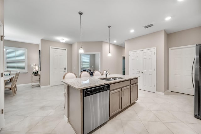 kitchen with light stone counters, sink, an island with sink, hanging light fixtures, and stainless steel appliances