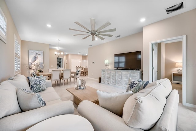 living room featuring ceiling fan with notable chandelier and light tile patterned floors