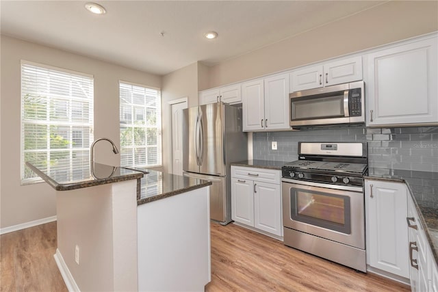 kitchen featuring white cabinets, a healthy amount of sunlight, appliances with stainless steel finishes, and light hardwood / wood-style flooring