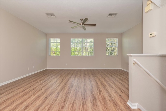 spare room featuring ceiling fan, light wood-type flooring, and a wealth of natural light