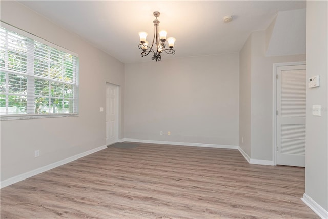 empty room with a chandelier and light hardwood / wood-style floors