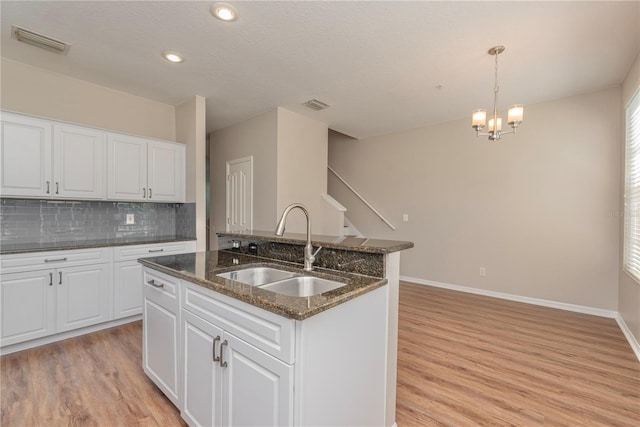 kitchen featuring a center island with sink, decorative light fixtures, white cabinets, and sink