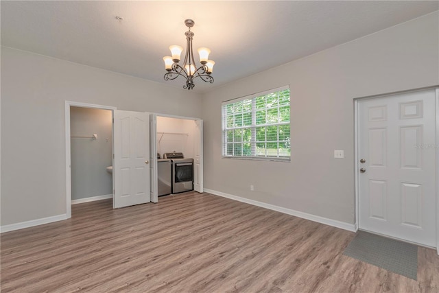 unfurnished living room featuring washer and clothes dryer, an inviting chandelier, and light wood-type flooring