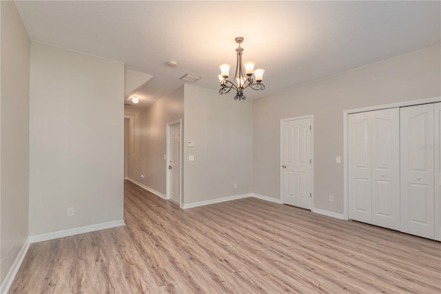 unfurnished room with a chandelier and light hardwood / wood-style flooring