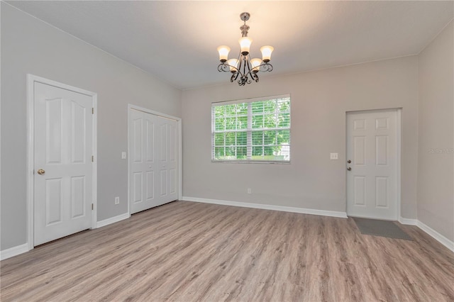 empty room with an inviting chandelier and light wood-type flooring