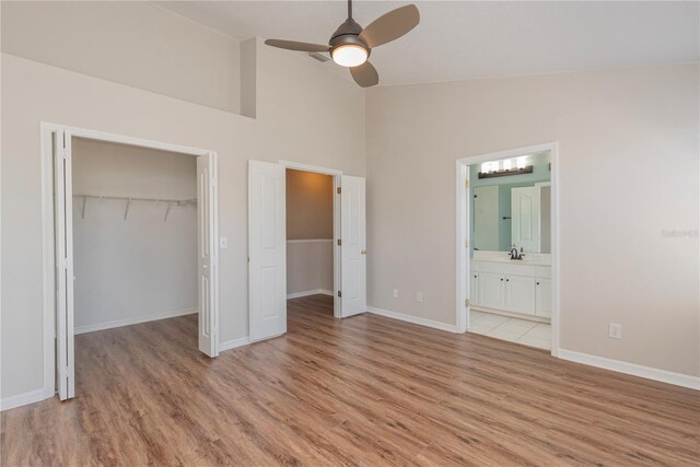 unfurnished bedroom featuring ensuite bath, ceiling fan, light hardwood / wood-style flooring, and high vaulted ceiling