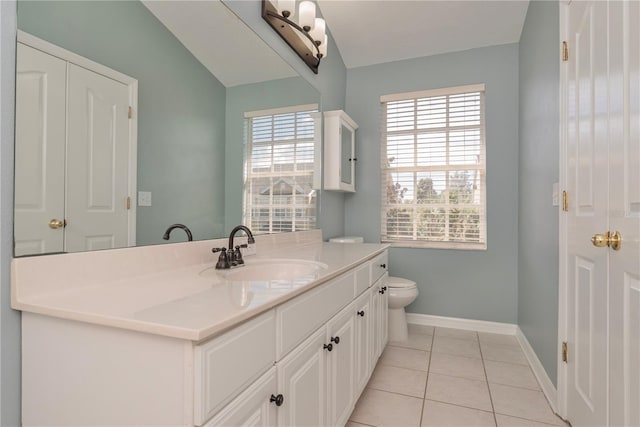 bathroom with toilet, vanity, tile patterned floors, and a wealth of natural light