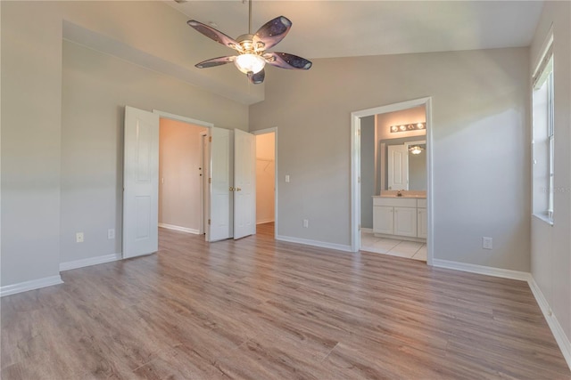 unfurnished bedroom featuring vaulted ceiling, ensuite bathroom, light hardwood / wood-style flooring, and ceiling fan