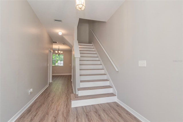 stairs featuring a chandelier and hardwood / wood-style flooring