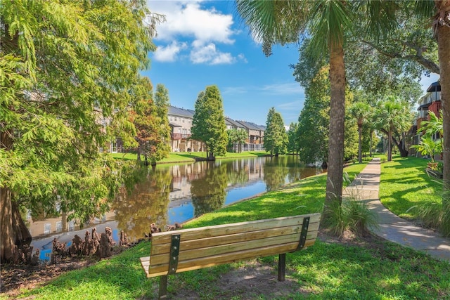 surrounding community with a water view and a lawn