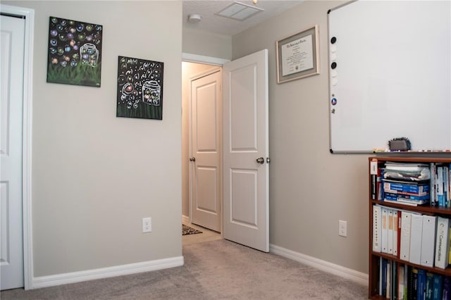 hallway featuring light colored carpet and a textured ceiling