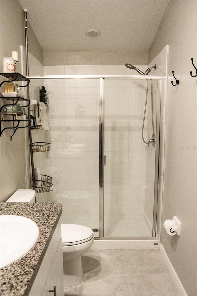 bathroom featuring vanity, toilet, a shower with door, and tile patterned floors