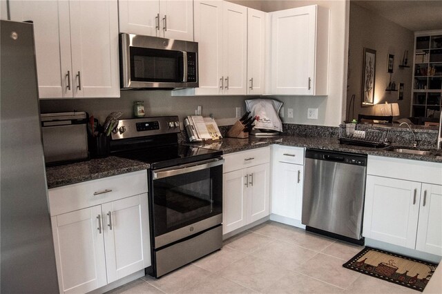 kitchen featuring dark stone countertops, stainless steel appliances, and white cabinets