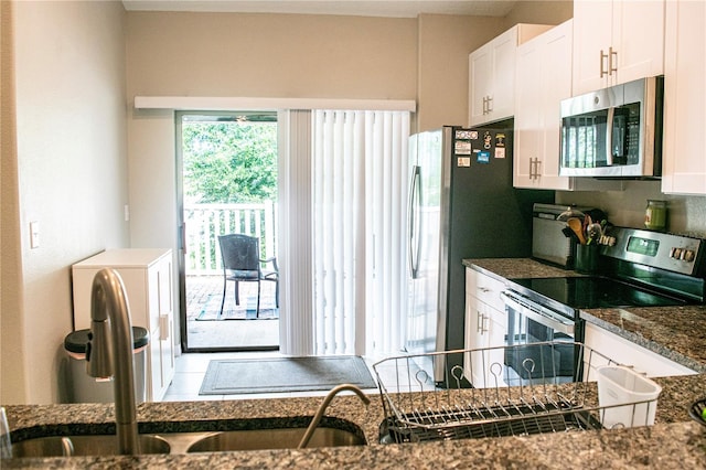 kitchen with dark stone countertops, appliances with stainless steel finishes, sink, and white cabinetry