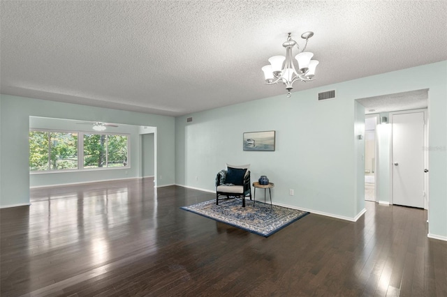 sitting room with dark wood-type flooring, ceiling fan with notable chandelier, and a textured ceiling