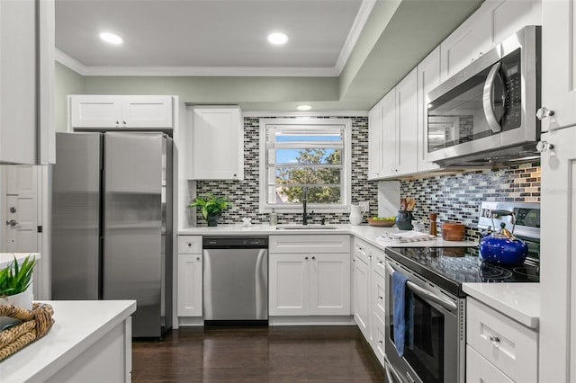 kitchen featuring sink, dark wood-type flooring, stainless steel appliances, ornamental molding, and white cabinets