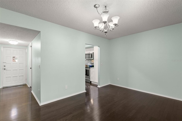 empty room featuring dark hardwood / wood-style floors, a notable chandelier, and a textured ceiling