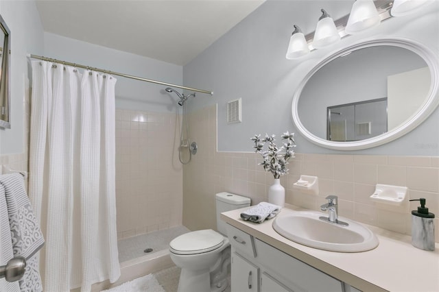 bathroom with vanity, toilet, a shower with shower curtain, and tile walls