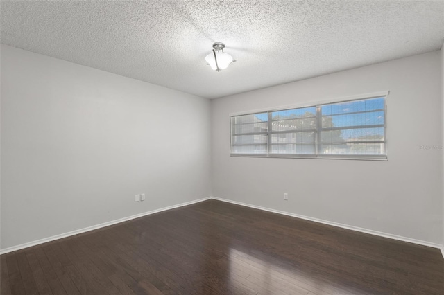 spare room with a textured ceiling and dark hardwood / wood-style flooring