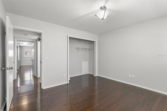 unfurnished bedroom with a textured ceiling, dark hardwood / wood-style flooring, and a closet