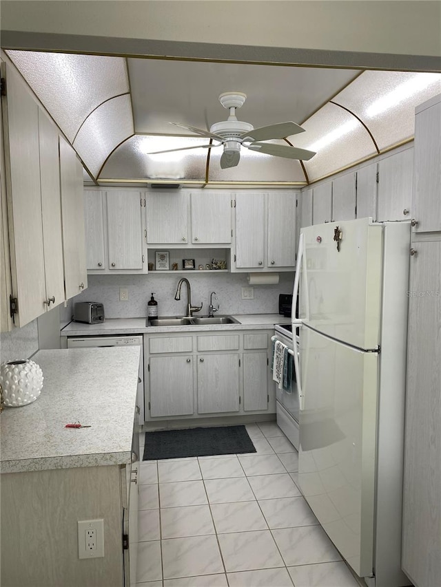 kitchen featuring ceiling fan, white refrigerator, stove, light tile patterned floors, and sink