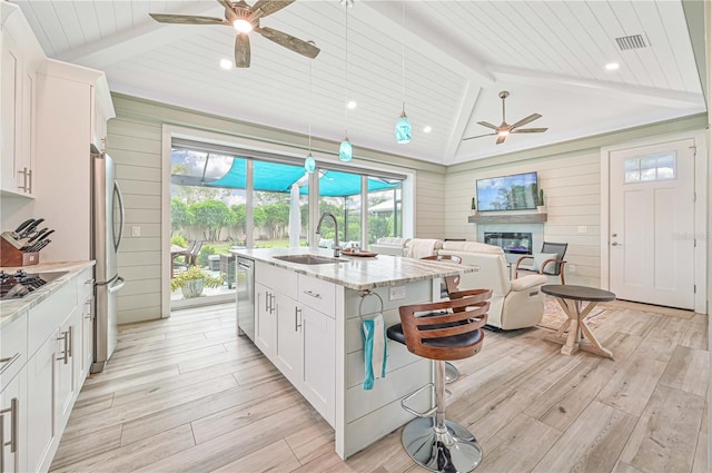 kitchen featuring ceiling fan, white cabinets, vaulted ceiling with beams, sink, and a center island with sink