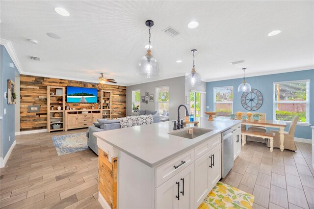 kitchen featuring a kitchen island with sink, sink, wood walls, decorative light fixtures, and ceiling fan