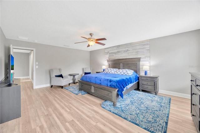 bedroom with light wood-type flooring, a fireplace, and ceiling fan