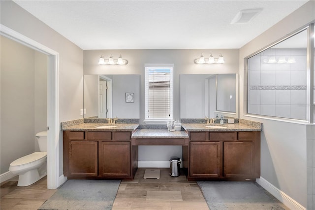 bathroom with hardwood / wood-style floors, a textured ceiling, vanity, and toilet