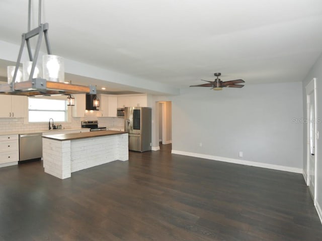 kitchen with dark wood-type flooring, sink, white cabinetry, a kitchen island, and appliances with stainless steel finishes