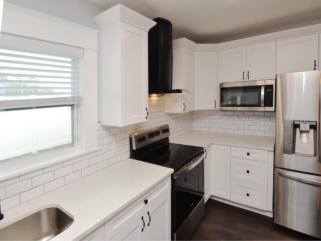 kitchen featuring appliances with stainless steel finishes, wall chimney exhaust hood, decorative backsplash, and white cabinetry