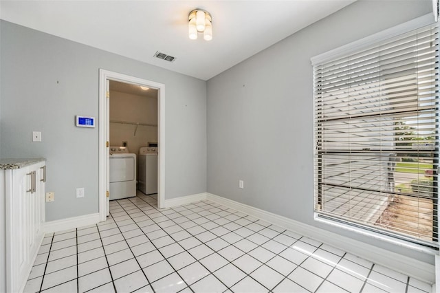 unfurnished room with separate washer and dryer and light tile patterned floors