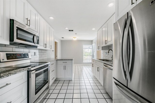 kitchen with stainless steel appliances, white cabinets, light tile patterned floors, and sink