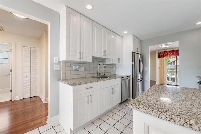 kitchen featuring sink, light stone countertops, white cabinets, and appliances with stainless steel finishes