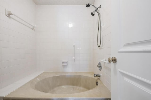 bathroom with tiled shower / bath and a textured ceiling