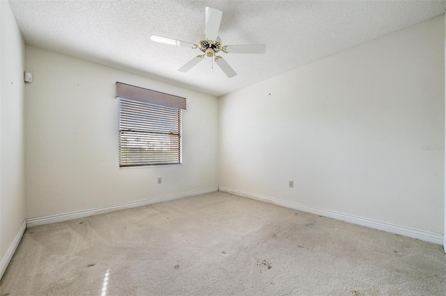 empty room featuring ceiling fan, light colored carpet, and a textured ceiling