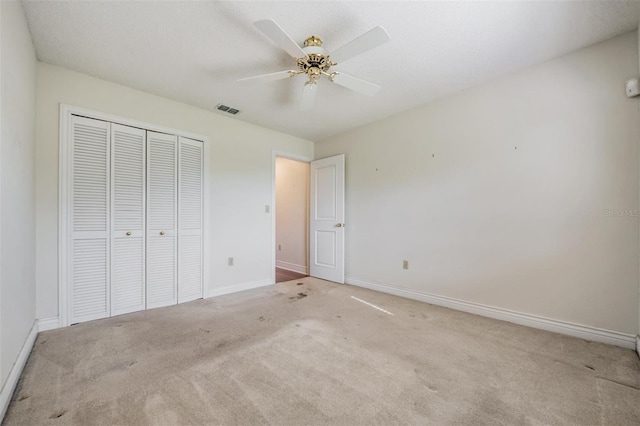 unfurnished bedroom featuring ceiling fan, light colored carpet, and a closet