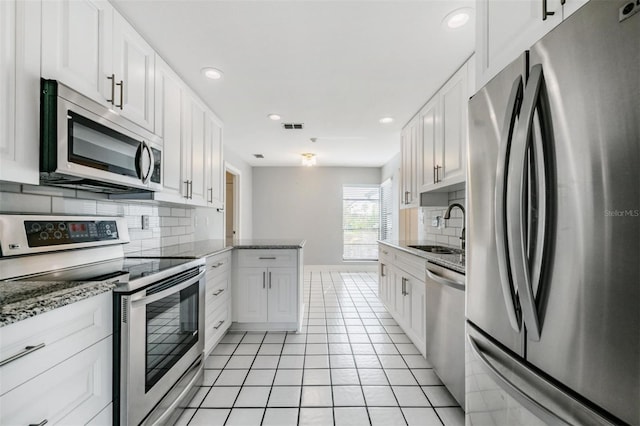 kitchen featuring white cabinetry, sink, light stone counters, and appliances with stainless steel finishes