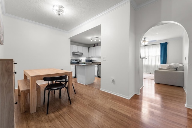 dining room featuring light hardwood / wood-style flooring, a textured ceiling, and crown molding