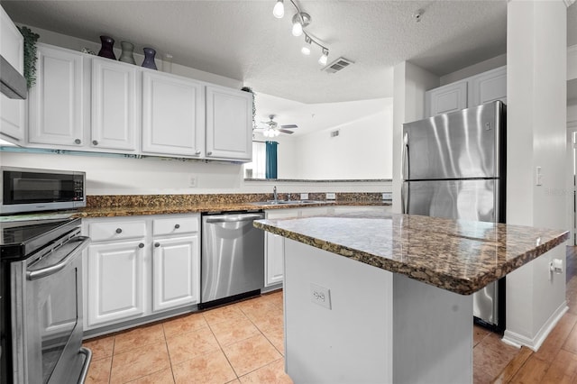 kitchen featuring ceiling fan, stainless steel appliances, and white cabinetry