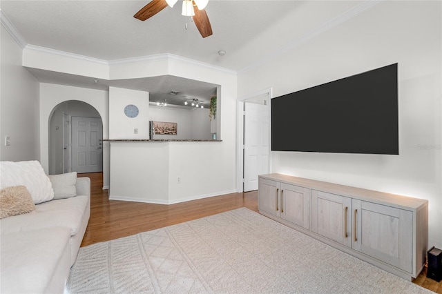 living room with ceiling fan, a textured ceiling, light hardwood / wood-style flooring, and ornamental molding