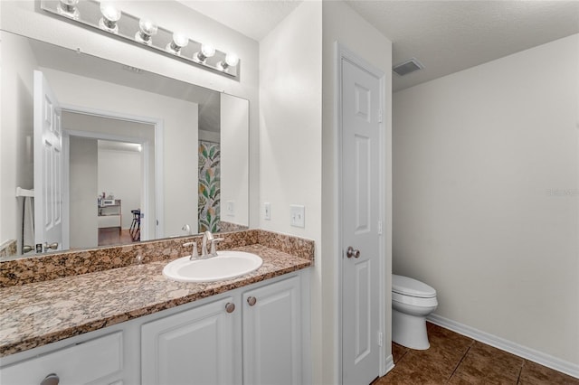 bathroom featuring tile patterned floors, a textured ceiling, vanity, and toilet