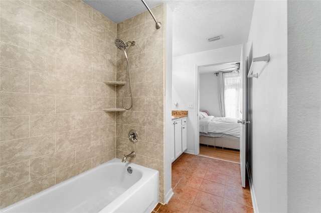 bathroom with vanity, tile patterned flooring, a textured ceiling, and tiled shower / bath