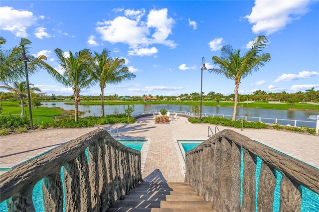 view of swimming pool featuring a water view and a patio area