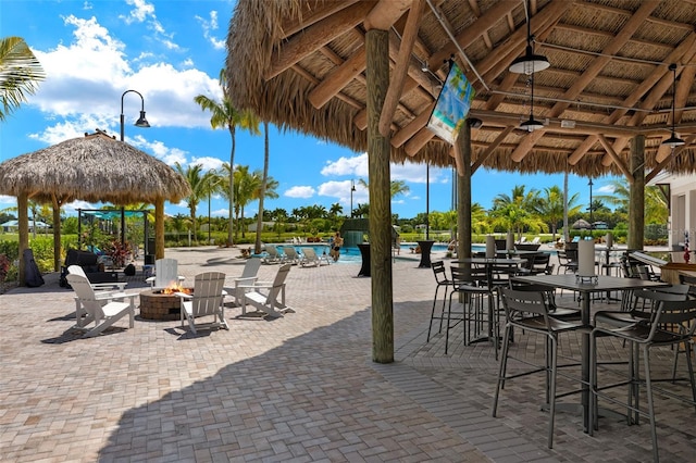 view of patio featuring a gazebo, ceiling fan, an outdoor fire pit, and a community pool