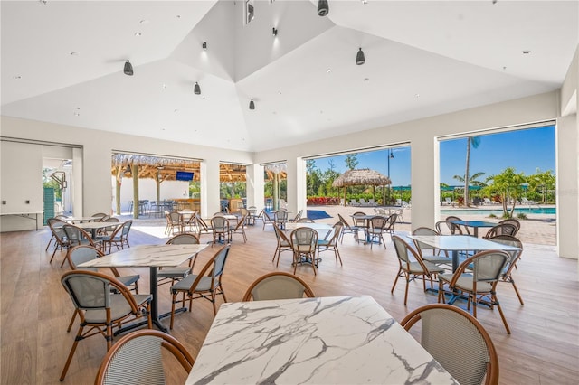 dining room with high vaulted ceiling and light hardwood / wood-style floors