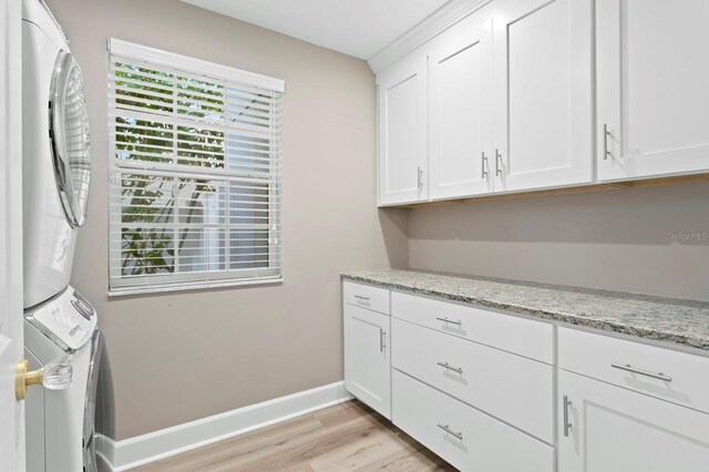 45 Adalia Ave, Tampa, FL 33606 - laundry area with cabinet space, stacked washer / dryer, light wood finished floors, and baseboards