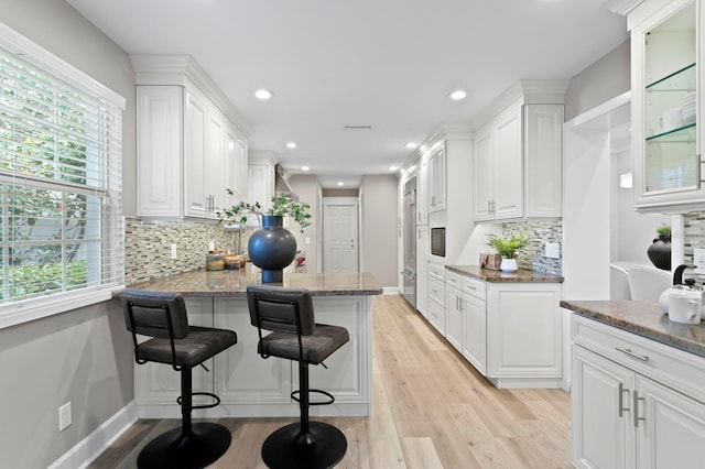 45 Adalia Ave, Tampa, FL 33606 - kitchen with white cabinets, light wood finished floors, stone counters, a breakfast bar area, and a peninsula