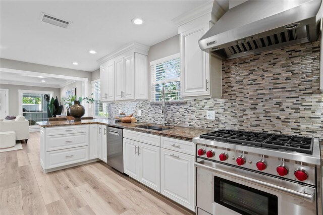 45 Adalia Ave, Tampa, FL 33606 - kitchen with wall chimney exhaust hood, stainless steel appliances, dark stone countertops, white cabinetry, and backsplash