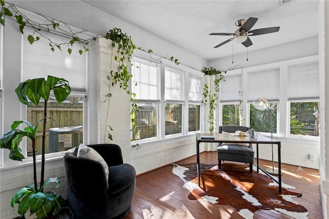 home office with a textured ceiling, dark hardwood / wood-style floors, ceiling fan, and brick wall